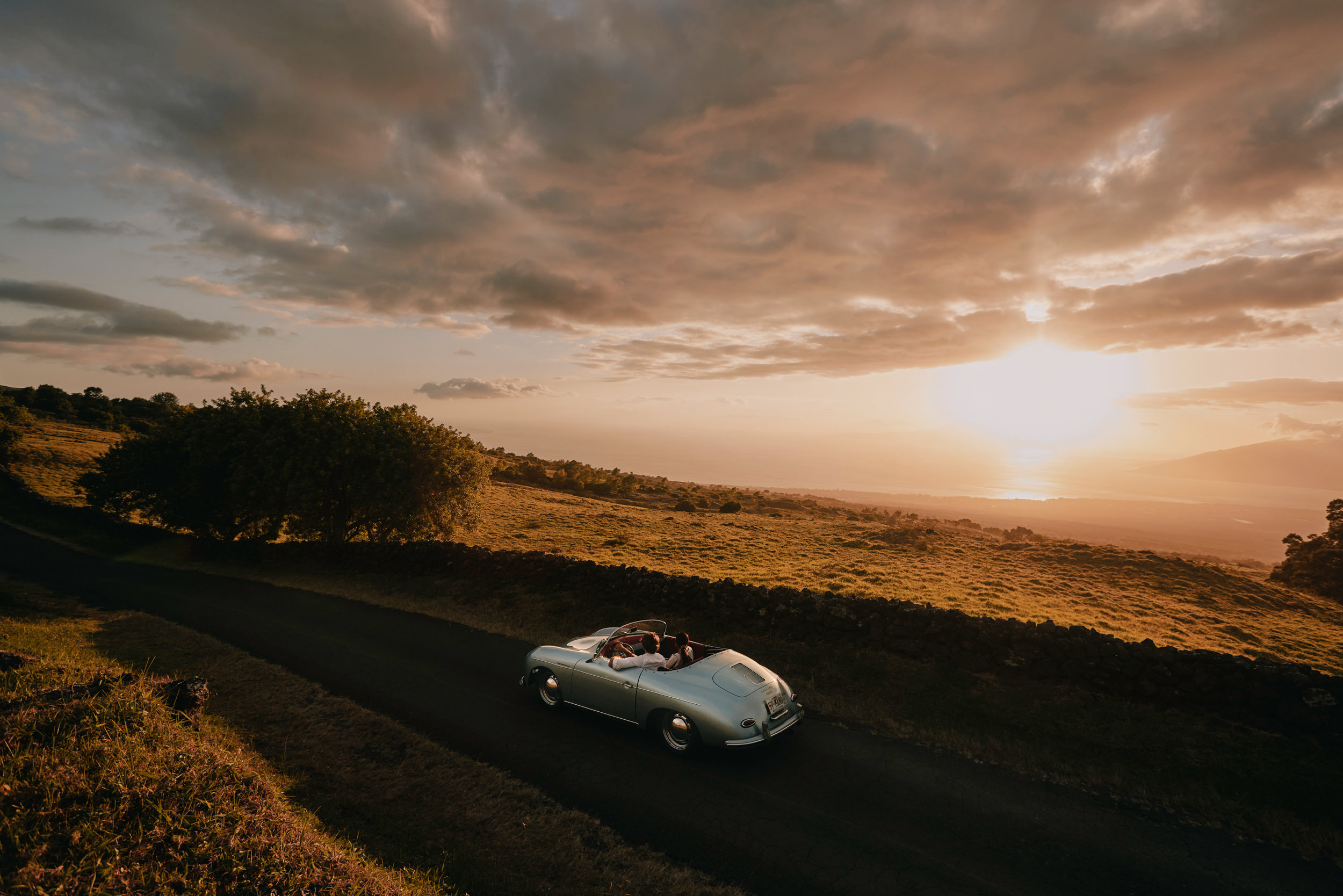 a couple driving in an old car at sunset