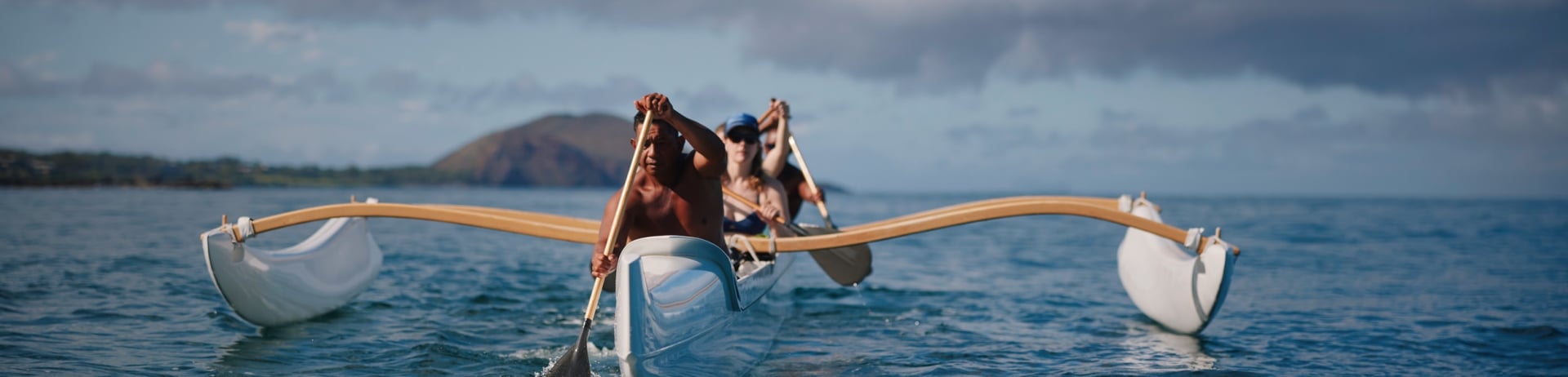 a group paddling an outrigger canoe