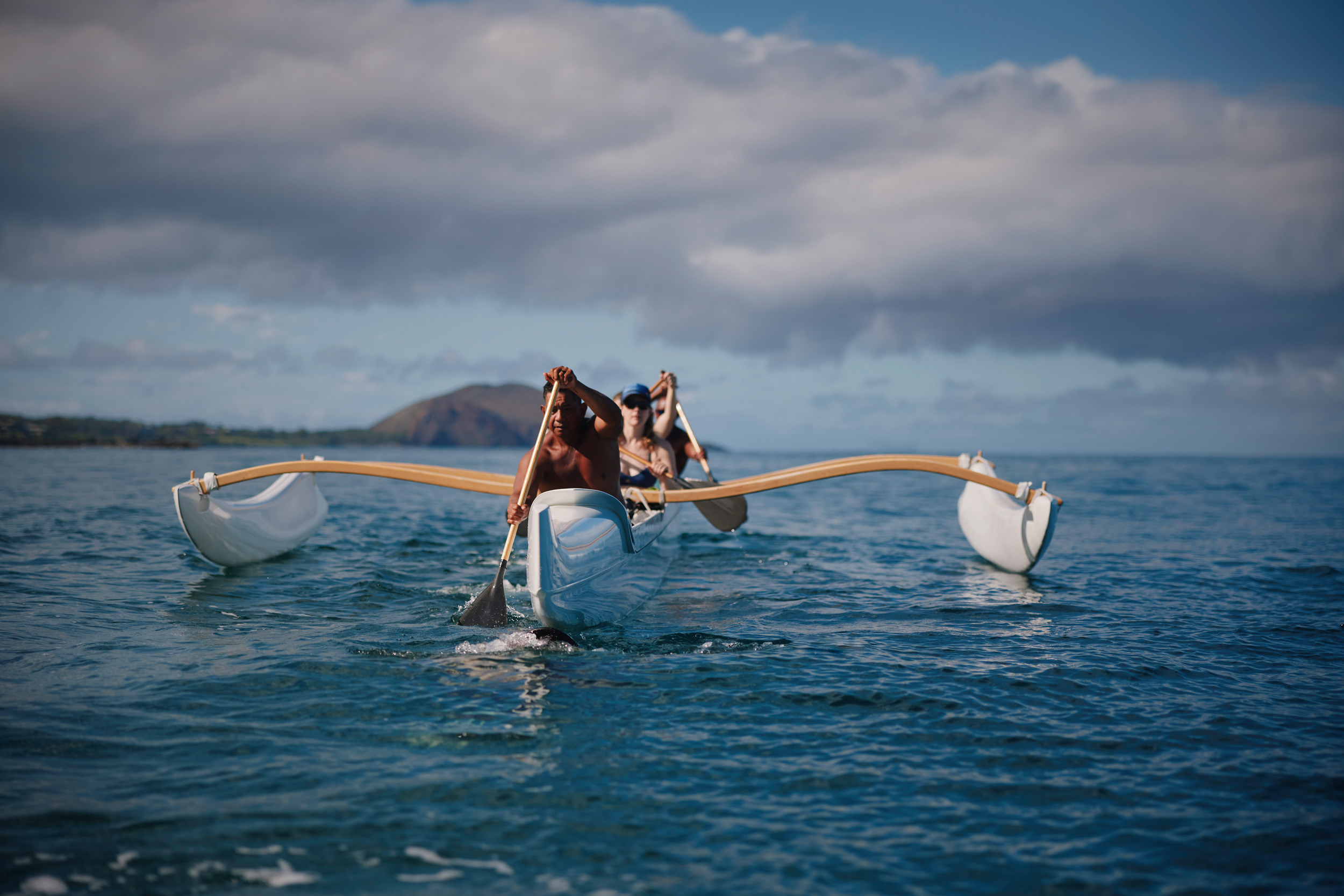 a group paddling an outrigger canoe