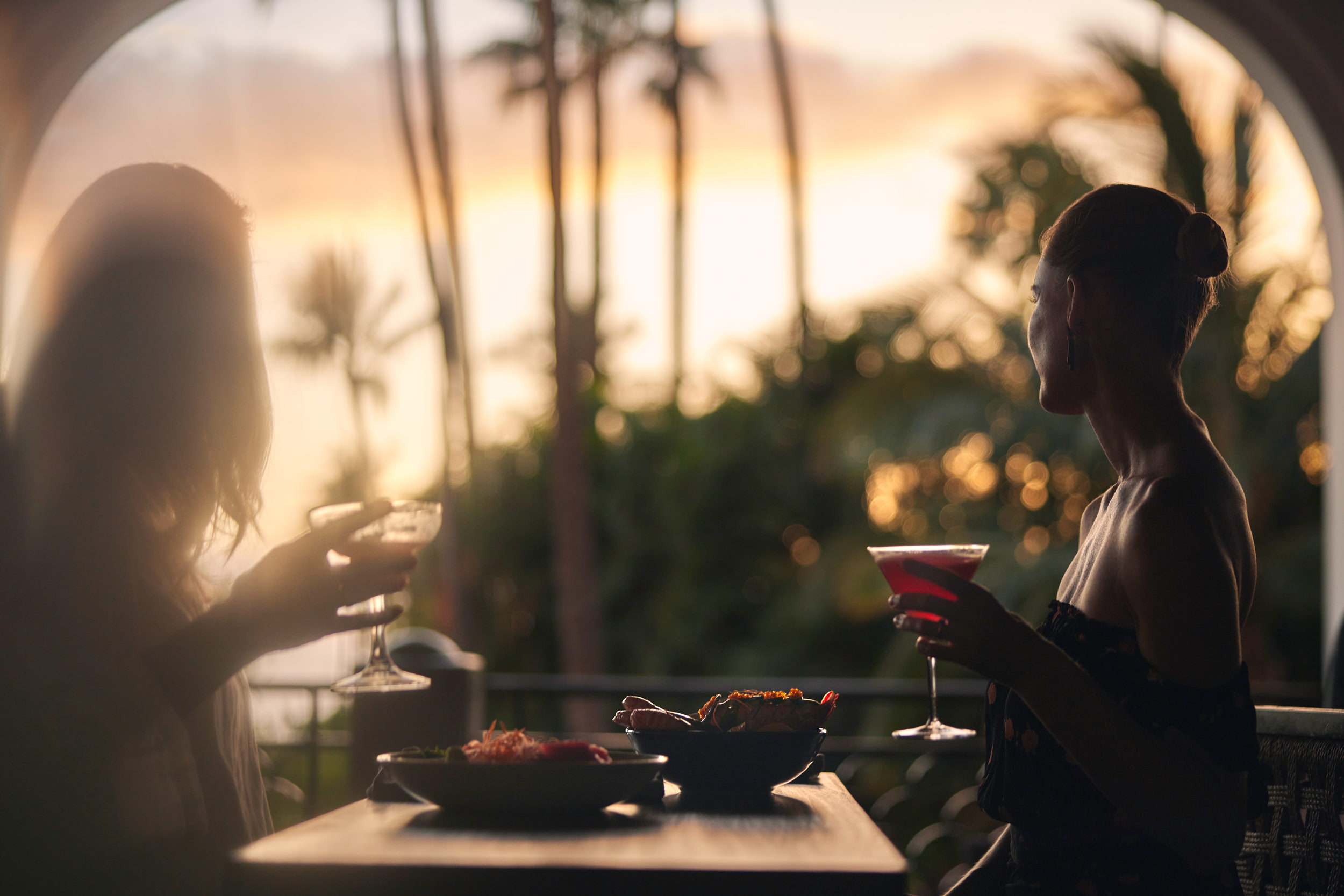 two women drinking cocktails watching the sunset