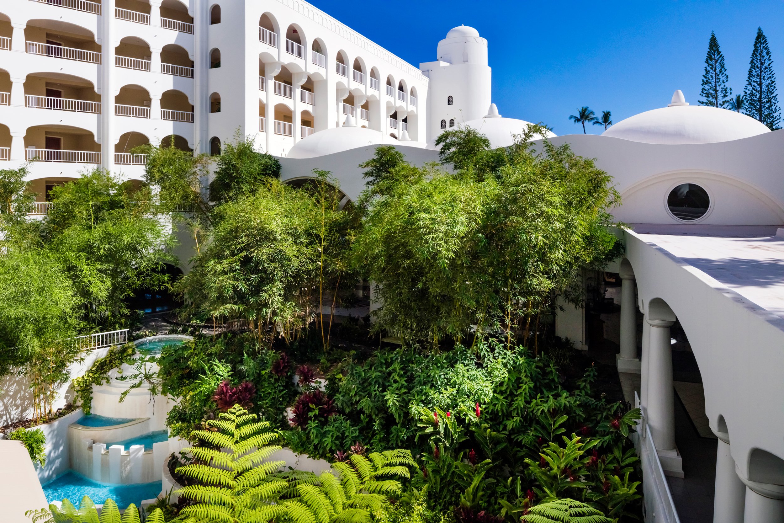 slight aerial of the resort garden and pool water fountain