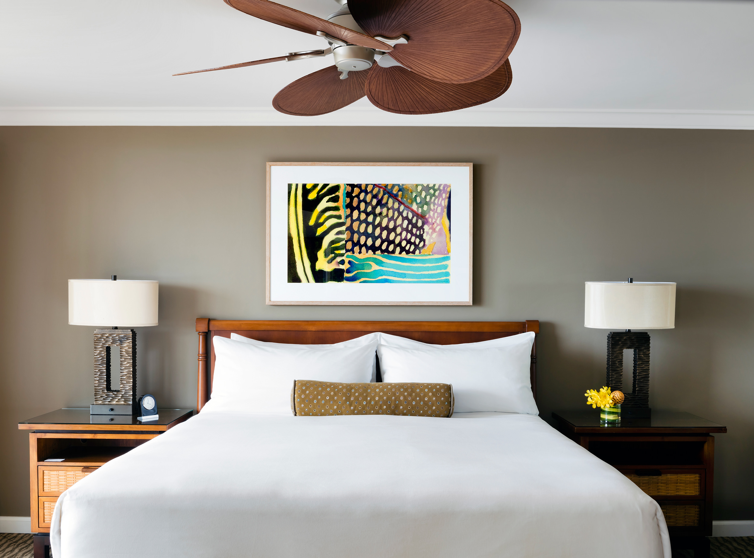 bedroom with colourful artwork and large ceiling fan