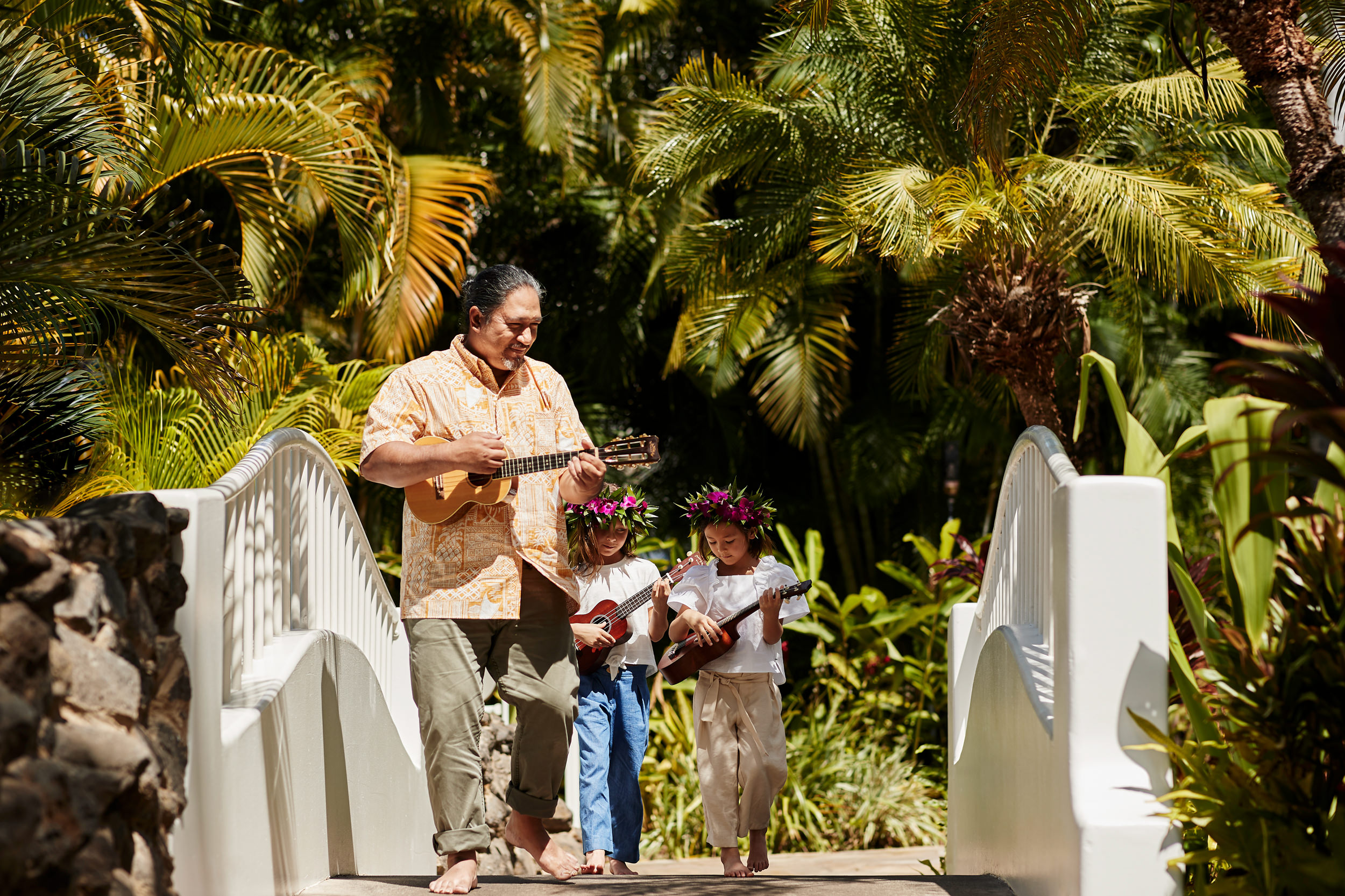 a man leading two girls in playing the `ukulele