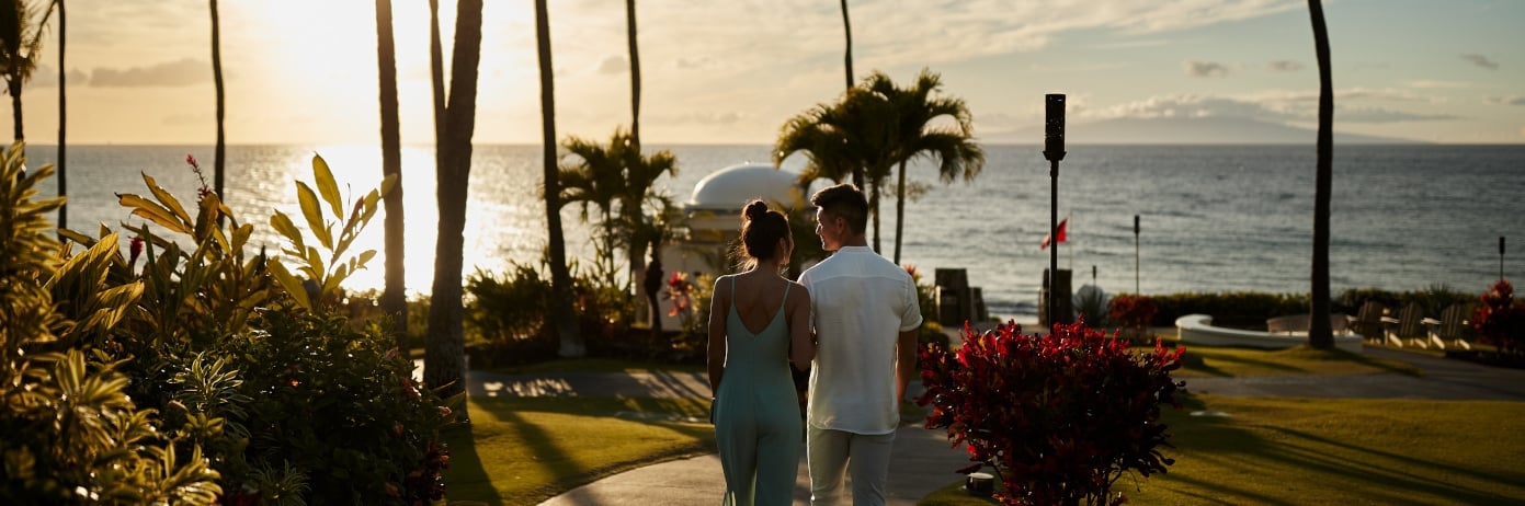a couple walking towards a beach at sunset