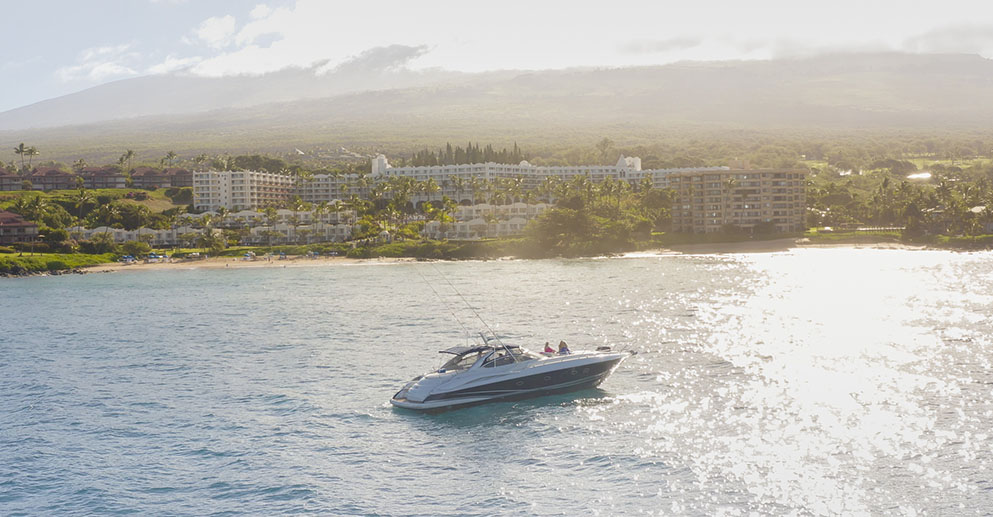 a boat in the ocean with a view of fairmont kea lani in the background