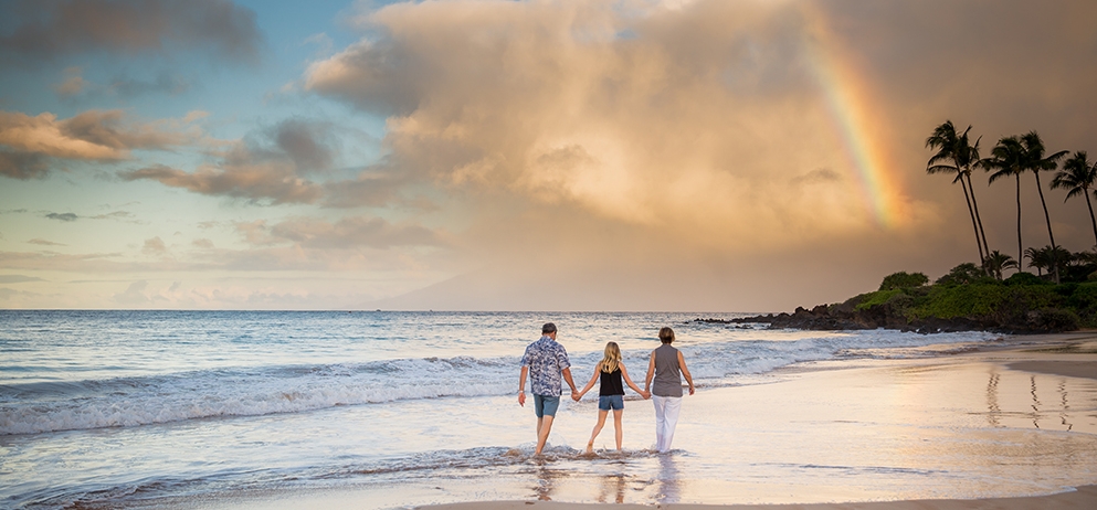 family holding hands and walking along the beach