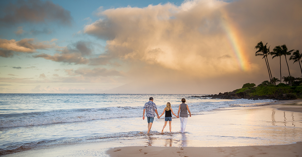 family holding hands and walking along the beach