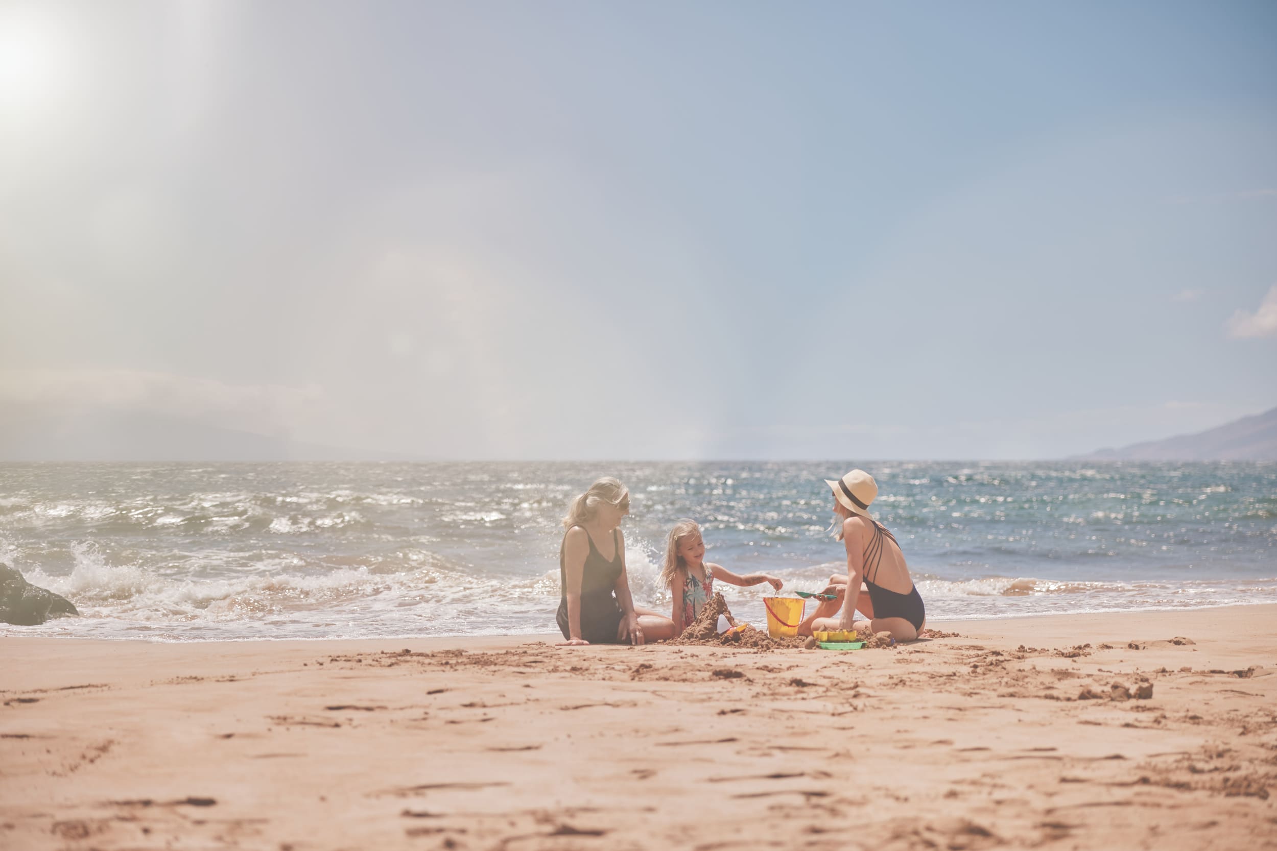 family playing with sand on the beach