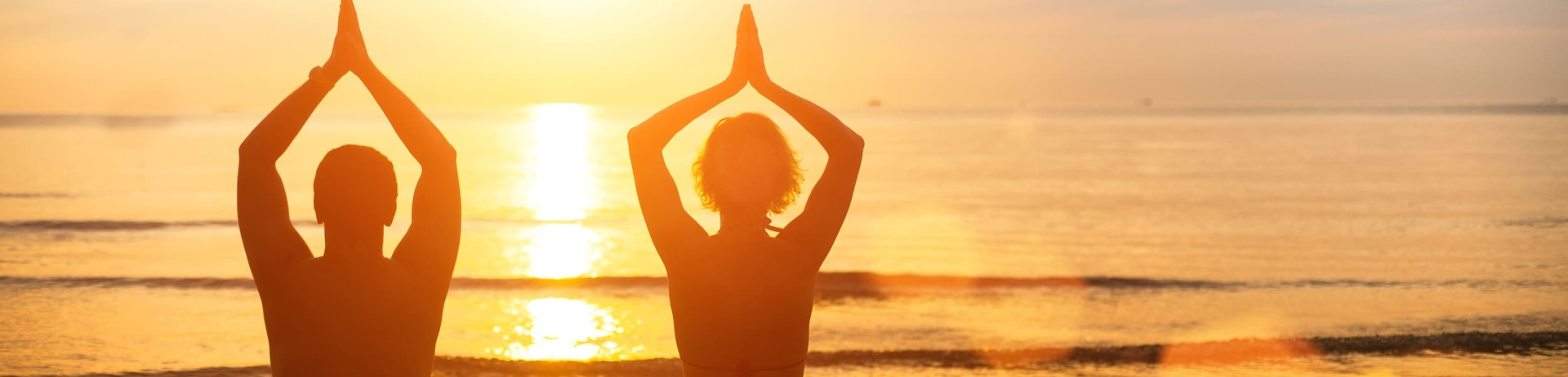 a couple doing yoga on the beach